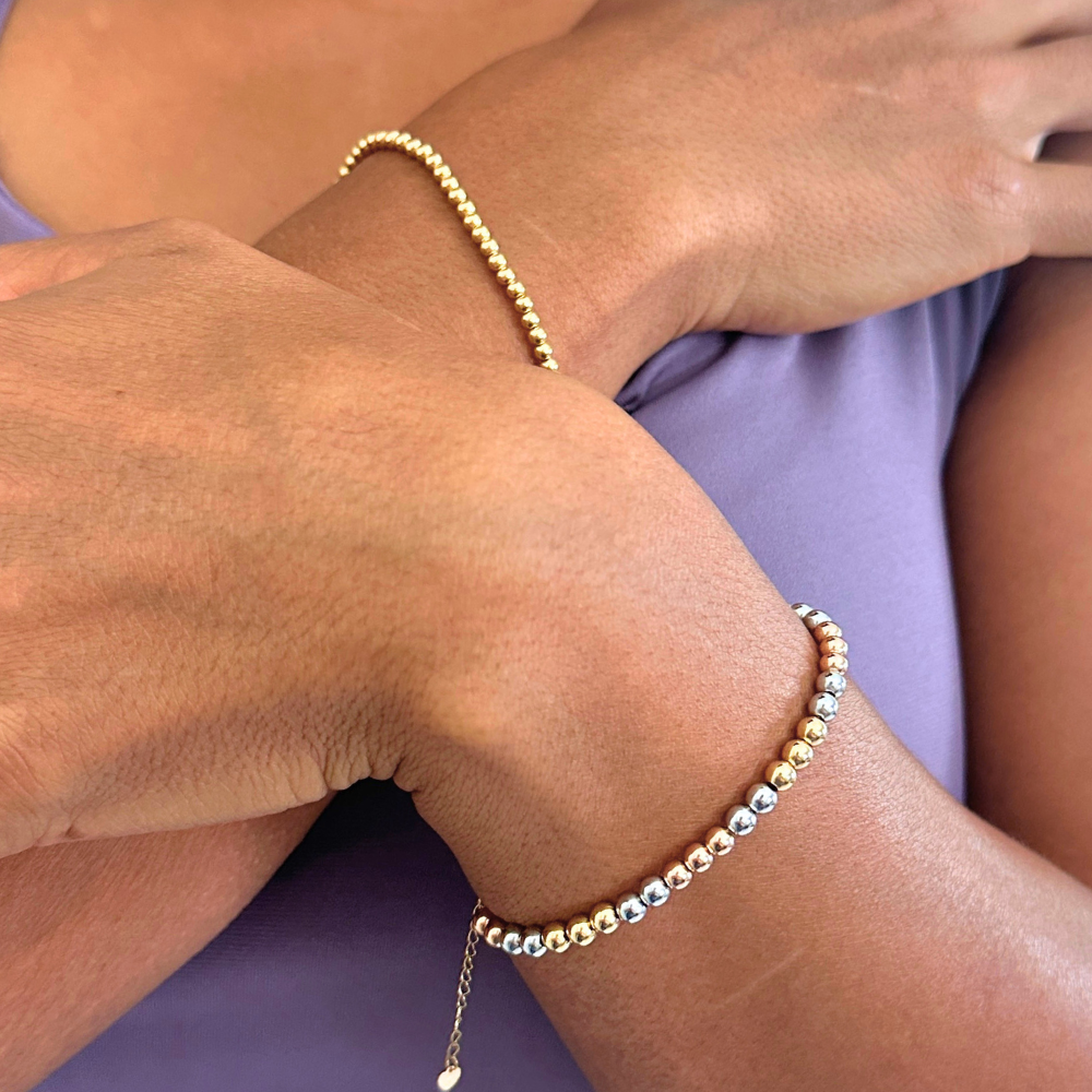 Close-up of a person's wrist wearing a gold beaded bracelet.