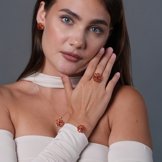 Amour Toujours Woman wearing red floral jewelry against a gray background