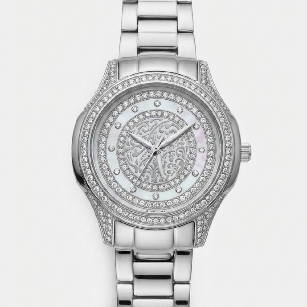 A Tony Valentino silver-tone metal link bracelet watch with a round bezel and dial encrusted with clear rhinestones, featuring a central mother-of-pearl style dial with an ornate monogram design.