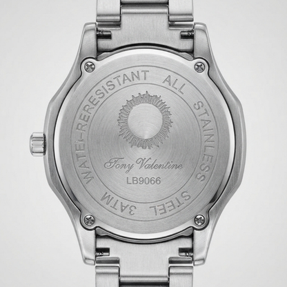 Tony Valentino Close-up of the back of a stainless steel wristwatch with a metal link band, showing engraved text and a sunburst logo on a light gray background.