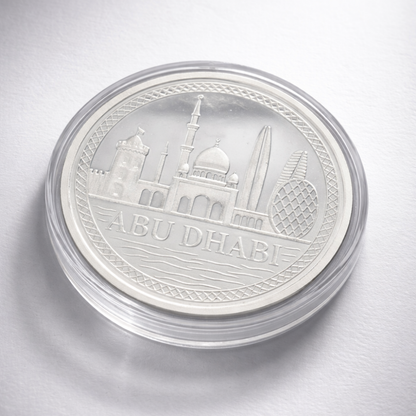 Silver coin with 'Abu Dhabi' and architectural design on a white background