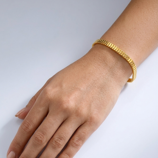 21k Gold bracelet on a wrist against a light gray background