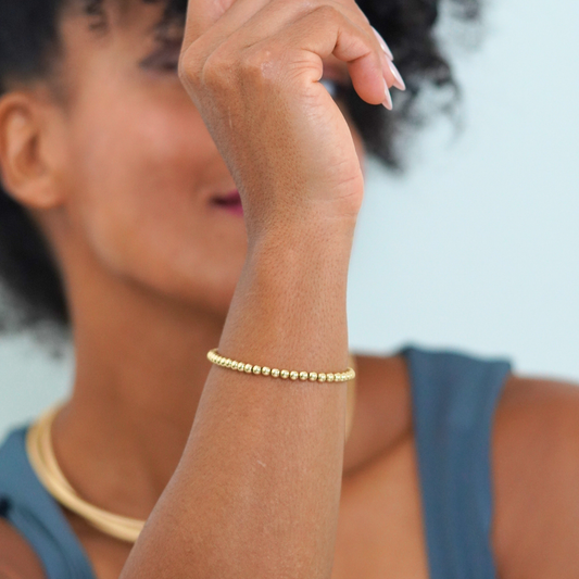 Woman wearing a gold bracelet on a blurred background