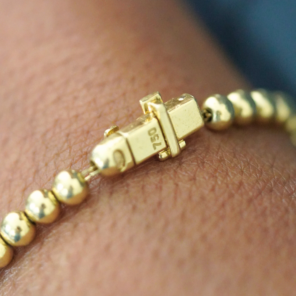 Gold beaded bracelet with a clasp on a wrist