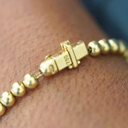 Gold beaded bracelet with a clasp on a wrist