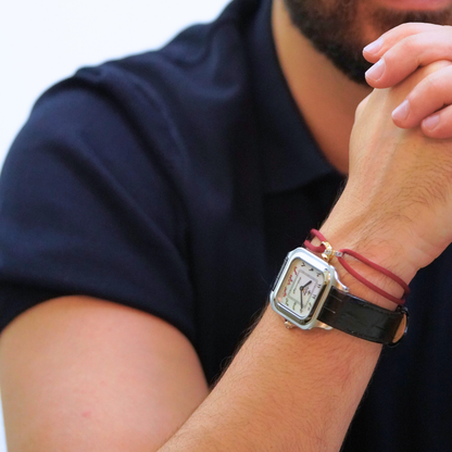 7 Emirates the Watch. Person wearing a watch with a black strap and red accents on a white background