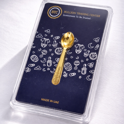 Gold spoon on a Bullion Trading Center card with patterns and branding.