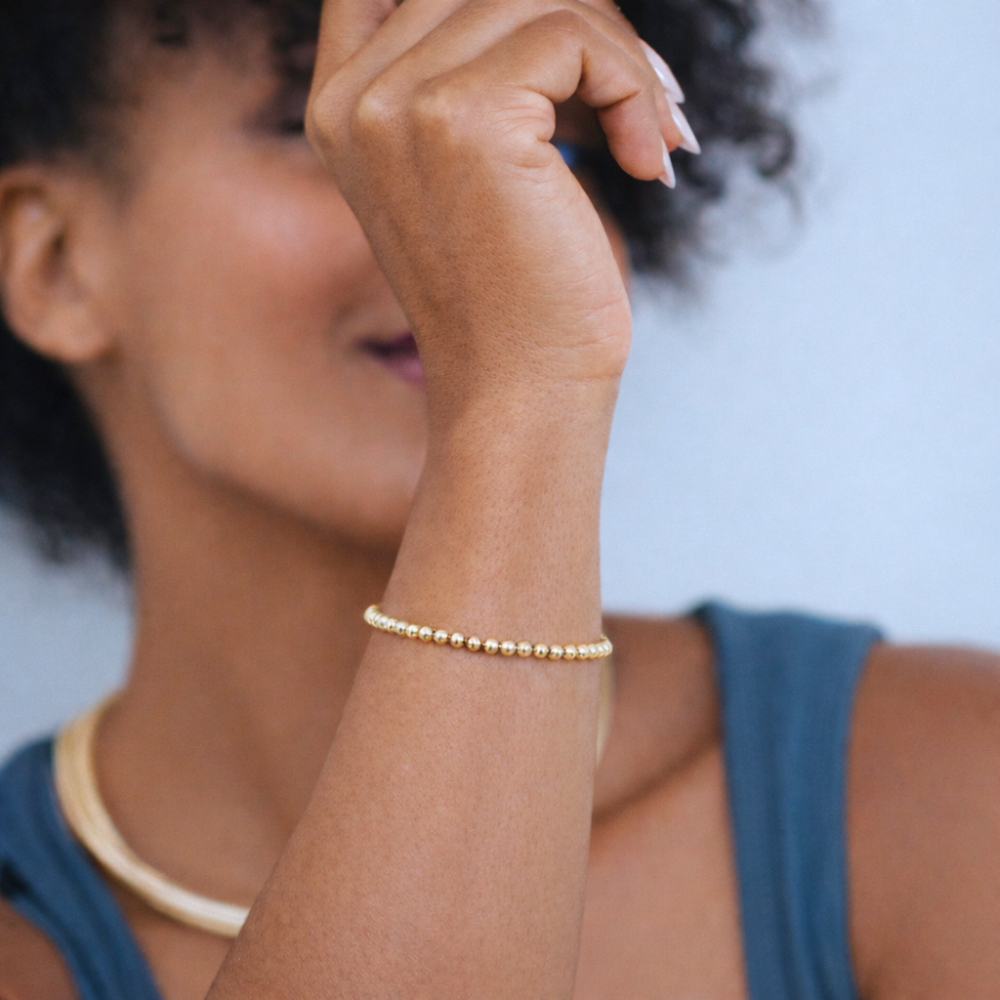 Woman wearing a gold bracelet on a light blue background